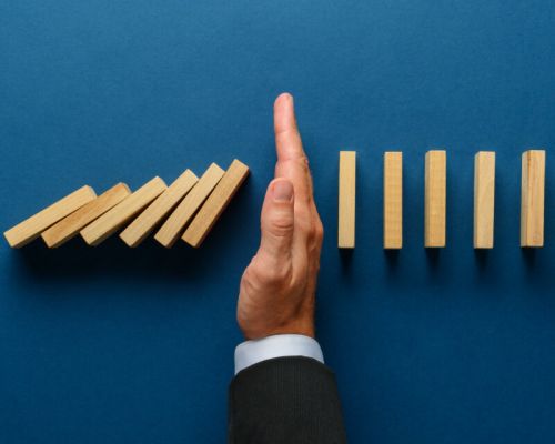 Wide,View,Image,Of,Businessman,Hand,Stopping,Collapsing,Dominos,In